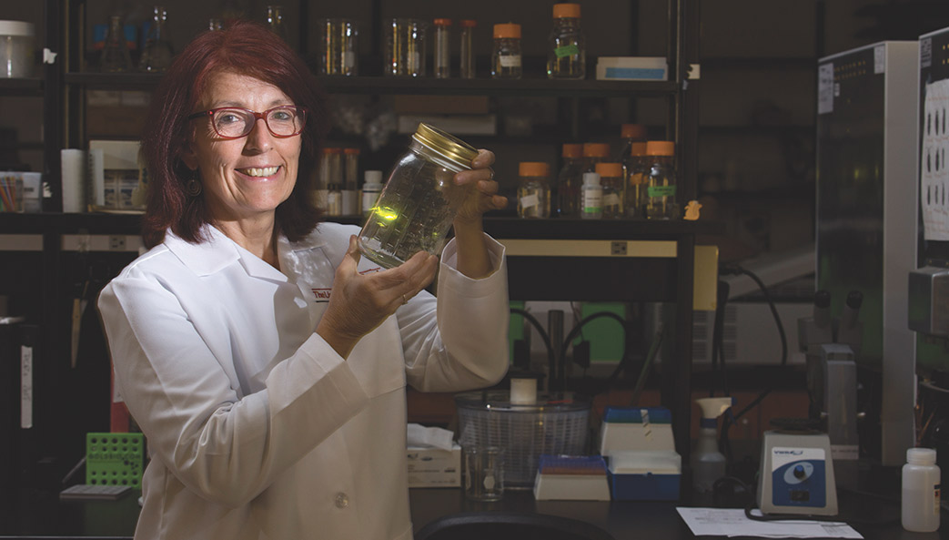 University of Georgia researcher Kathrin Stanger-Hall poses for a photo with a firefly in a glass jar