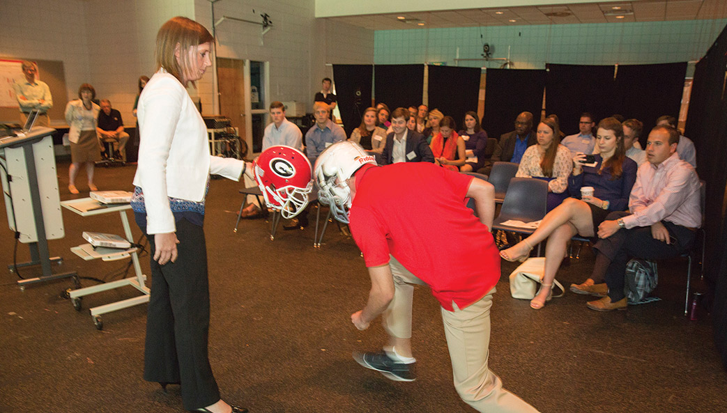 Wearing a helmet wired with accelerometers, Travis Fetchko, a research assistant, hits a helmet held by Julianne Schmidt, an assistant professor in the College of Education.