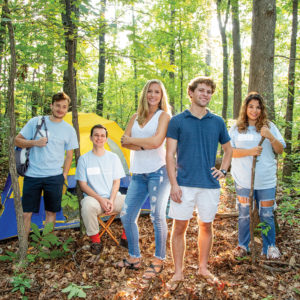 Five students in woods by tent